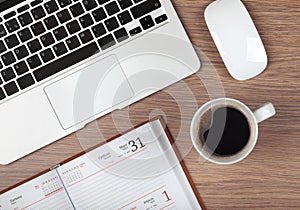 Notepad, laptop and coffee cup on wood table