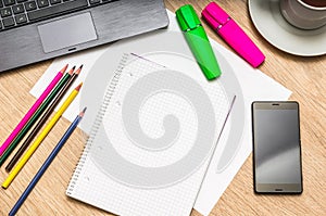 Notepad, mobile phone, paper, pencils and laptop on table