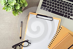 Notepad mock up with laptop computer, notebooks and plant on modern office desk. Top view, flat lay