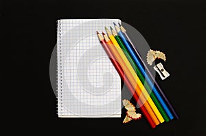 Notepad for notes and color pencils on black background.