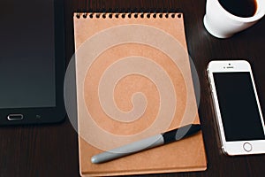 Notepad on an office desk, coffee and electronic gadgets, phone, tablet