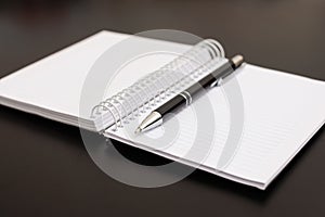 Notepad and pen on black wooden table.