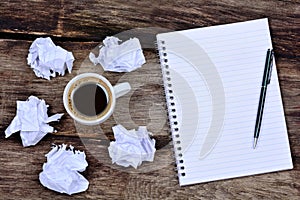 Notepad with pen coffee and crumpled paper on desk