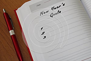 Notepad with a pen on a wooden table. View from above. The concept of goals for the new year