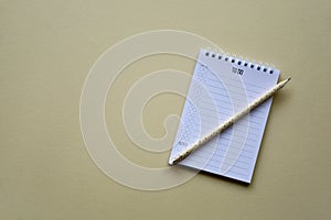 Notepad with pencil on a beige paper background. Top view. Flat lay.