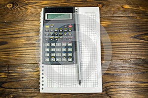 Notepad with pencil and calculator on wooden desk