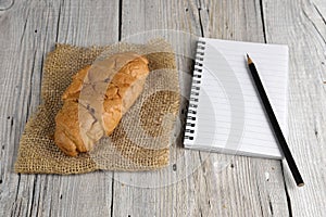 Notepad with pencil and croissant