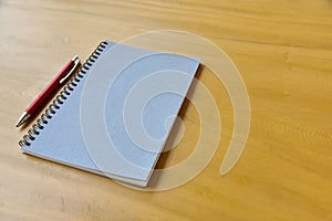 Notepad and a pencil on wooden desk background