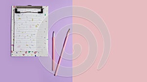 Notepad with a pencil for writing text. on a pink and lilac paper background