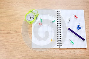 Notepad with purple pen, paper,clips and alarm clock