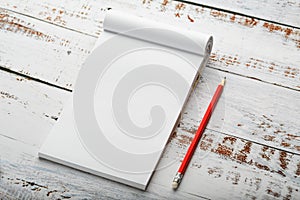 Notepad with a red pencil on a white wooden table against the background, for education, recording goals and deeds