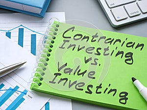 Notepad with sign contrarian investing vs value investing. photo