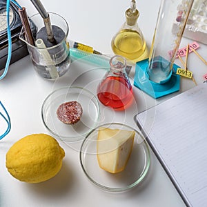 Notepad, tablets with additives E, test tubes and laboratory equipment. Food laboratory. Close up on a white table