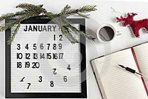 Notepad for taking notes of goals and plans for the new year, calendar,a cup of coffee, Christmas tree decorations on the desktop