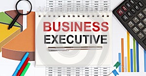 Notepad with text BUSINESS EXECUTIVE on business charts and pen and charts