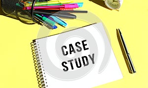 Notepad with text CASE STUDY with stationery. Yellow background color.