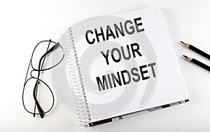 Notepad with text CHANGE YOUR MINDSET . White background. Business concept