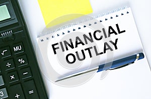 Notepad with text Financial Outlay. Calculator, pen and stickers photo
