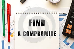 Notepad with the text FIND A COMPROMISE on a color financial chart. Business concept