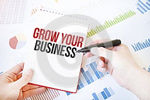 Notepad with text GROW YOUR BUSINESS. Diagram and white background