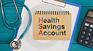 Notepad with text Health Savings Account HSA, calculator and stethoscope