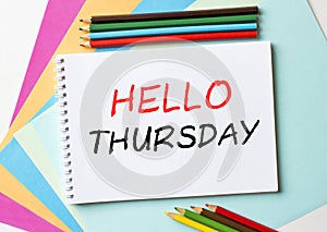 The Notepad with the text Hello Thursday is on colored paper with color pencils