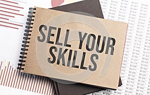 Notepad with text SELL YOUR SKILLS on a charts and numbers. Business concept