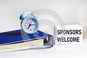 Notepad with text Sponsors Welcome. Folder with documents and a clock on a white background. financial concept