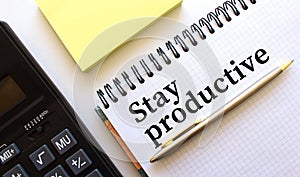 Notepad with text STAY PRODUCTIVE, next to it lies a calculator. Business concept