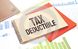 Notepad with text TAX DEDUCTIBLE. Diagram, red notepad and white background