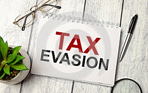 Notepad with text tax evasion with office supplies