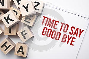 Notepad with text time to say good bye and wooden cubes with letters