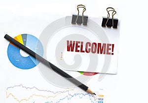 Notepad with text WELCOME on business charts and pen