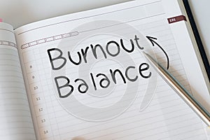 notepad with text written BURNOUT AND BALANCE, concept of a hardworking worker trying to avoid burnout and finding a balance to