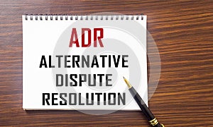Notepad with title Alternative Dispute Resolution ADR on the table
