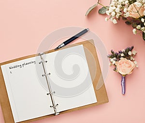 Notepad with wedding planning checklist and bridal flower bouquet composition, creative background