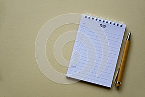 Notepad with wooden pen on a beige paper background. Top view. Close-up.