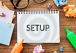 Notepad on a wooden table. The word is SETUP