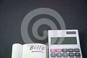 Notepad with the words, Bills with calculator by the side. Black background
