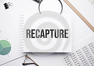 On the notepad for writing the text recapture, magnifier,charts and glasses