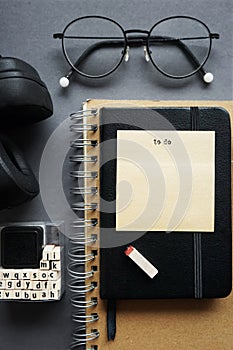 Notepads next to pen, sticky notes, glasses and headphones