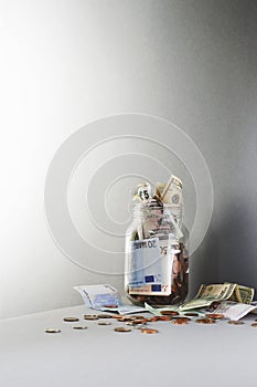 Notes and coins overflowing from jar