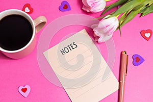 Notes with pen, cup of coffee, tulip spring flower and cute hearts on pink background, flat lay