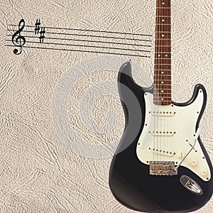 Notes and solid body classic electric guitar on right side of the light skin background.