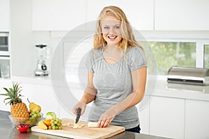 Nothing beats fresh fruit. Attractive curvaceous young woman chopping fruit in her kitchen.