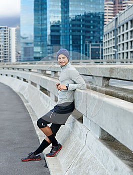 Nothing better than the city at dawn for running. a young jogger taking a break on the road in the early morning.