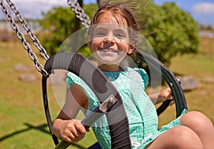 Nothing better than a swing. a young girl playing on a swing outsdie.