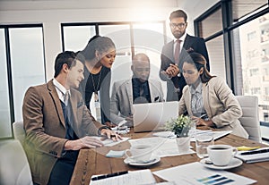 Nothing boosts productivity like teamwork. a group of young businesspeople using a laptop together during a meeting in a