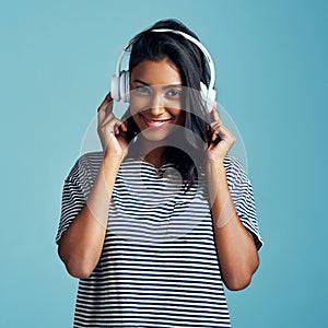 Nothing brings back good memories like music. a beautiful young woman wearing headphones against a blue background.