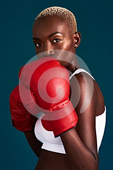 Nothing can or will stop me. Cropped portrait of an attractive young female boxer working out against a dark background